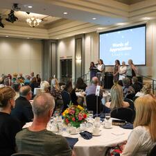 Photo of guests sitting at their tables and looking at those on stage