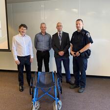 4 Adult males stand in front of wheelchair used by Eugene Reimer