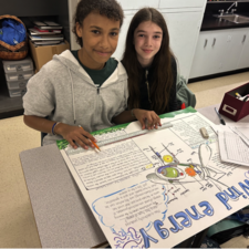 Students show their work on poster for wind energy.