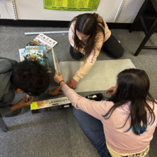 Students measuring friction on varying surfaces.