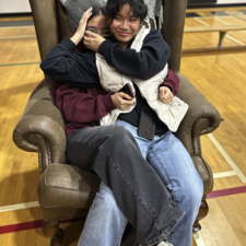 Friends hugging on a large chair.