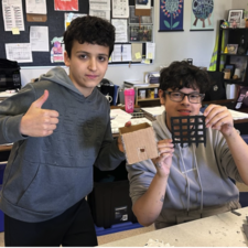 Two students hold up a structural piece of the castle